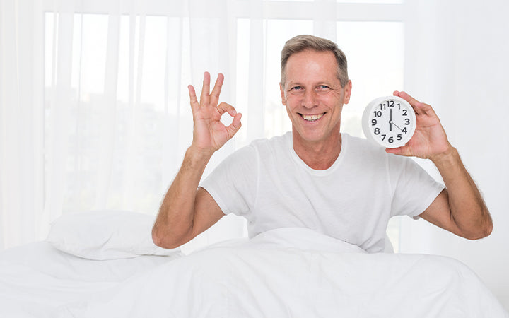 Man showing restored sleep cycle with clock, feeling rested.